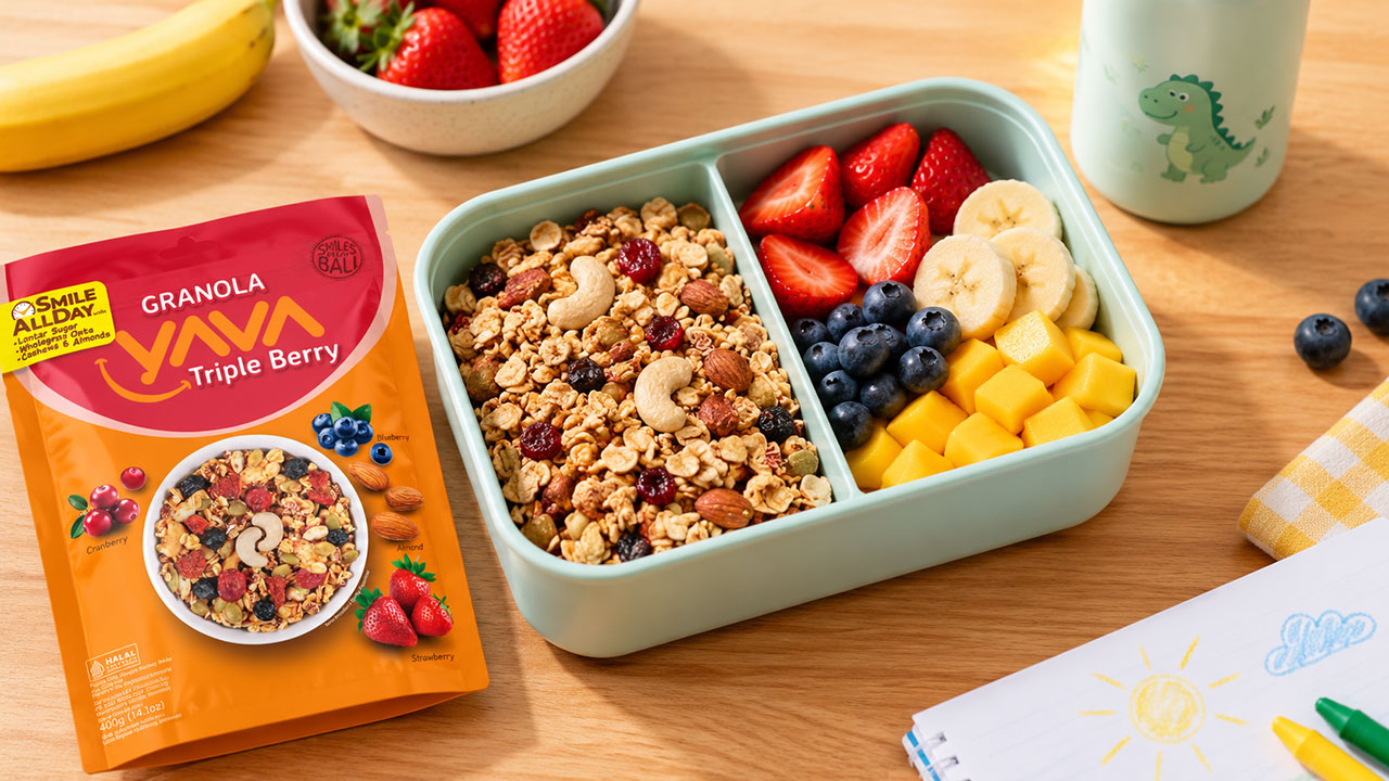 Kotak bekal anak berisi Granola YAVA dan potongan buah segar.
